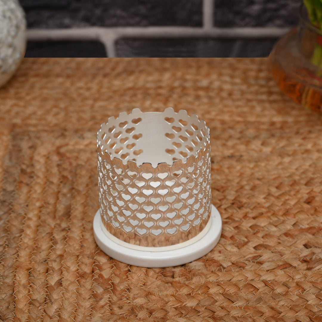 Heart Votive is a cylindrical silver candle stand pierced all over with a dense heart lattice, so a lit tealight throws a soft - angle 2