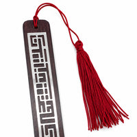 Enigma Bookmark is a silver bookmark carrying a geometric maze fretwork across a slim dark wood plaque, finished with a maroon tassel. - white background
