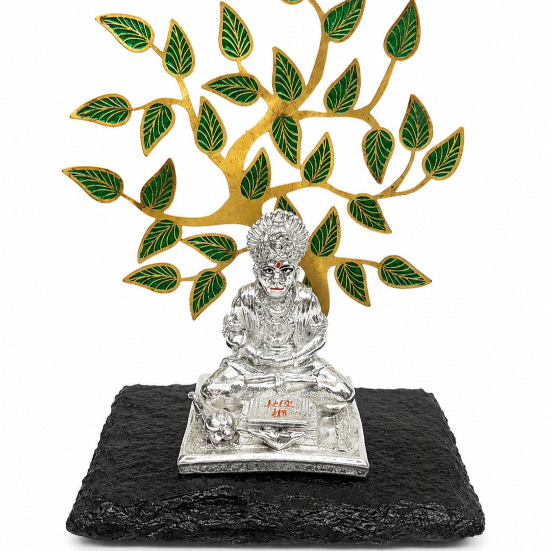 Hanuman Ji With Tree is a silver hanuman idol seated on an engraved chowki beneath a gold-finished tree with green enamelled leaves - white background