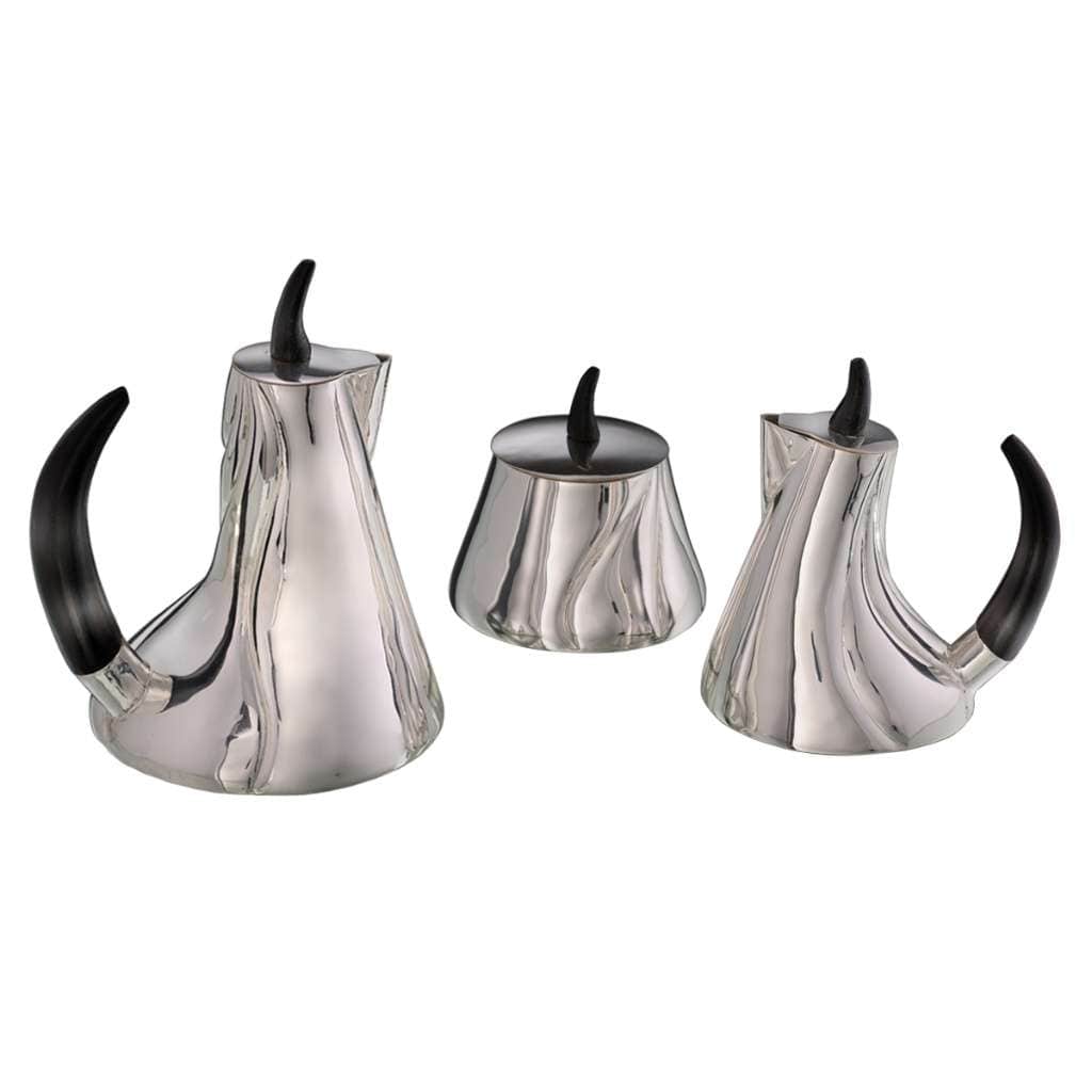 Tea Set Sublime is a silver teapot set that ripples like fabric caught mid-fall, its faceted, draped body topped with a bold - white background