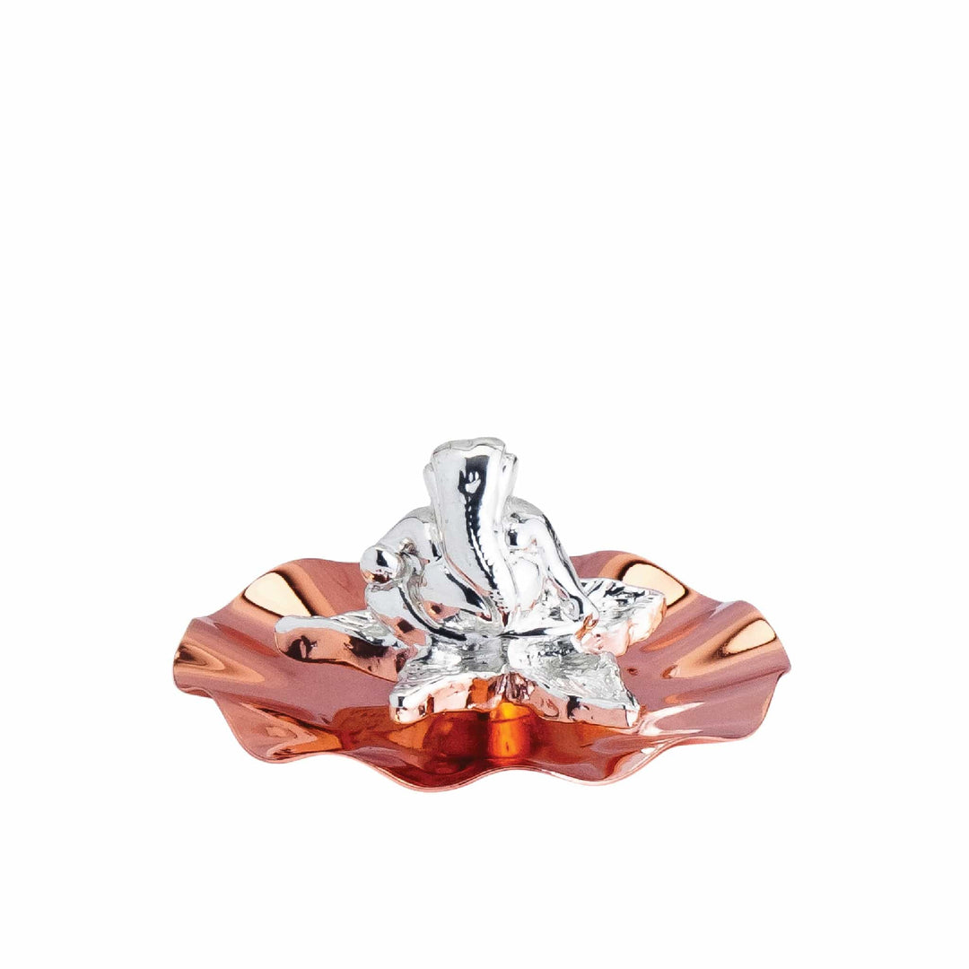 Tara Ganesha sits a small silver Ganesha idol at the centre of a wavy, flower-shaped dish - white background