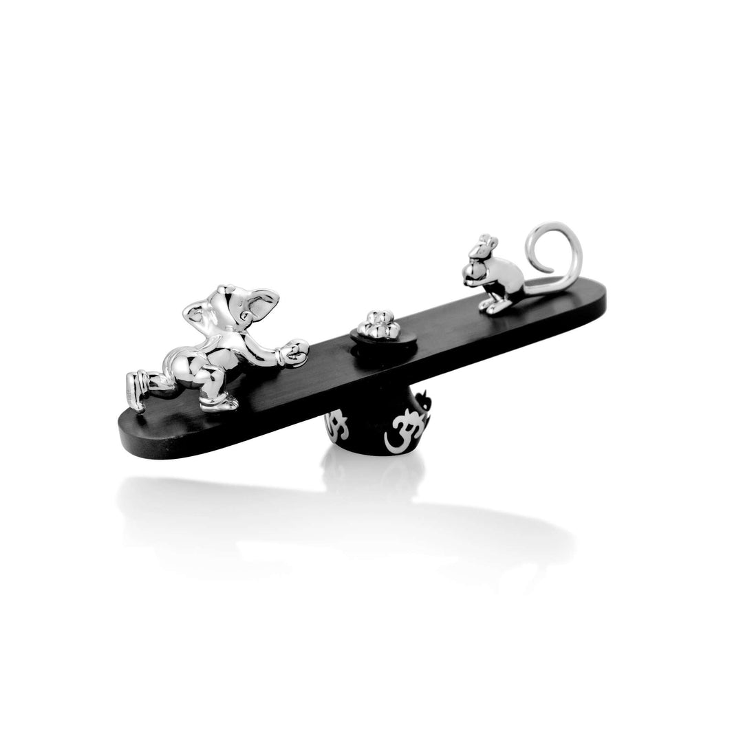 Ganesh Gopal is a sterling silver Ganesha idol that catches him young and playful, mid-crawl on one end of a wooden seesaw - white background