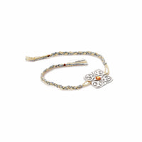 Rakhi Kavach is a silver rakhi with a scrollwork medallion set with a single amber stone on a braided cream and grey-blue thread. - white background