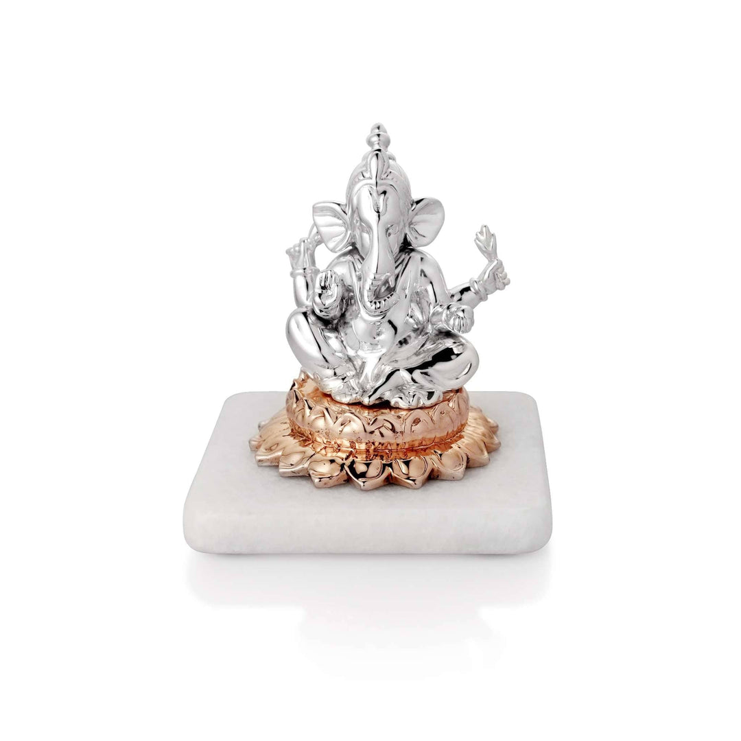Ganesh On Lotus is a crowned, finely detailed sterling silver Ganesha idol seated cross-legged on an open rose-gold lotus - white background