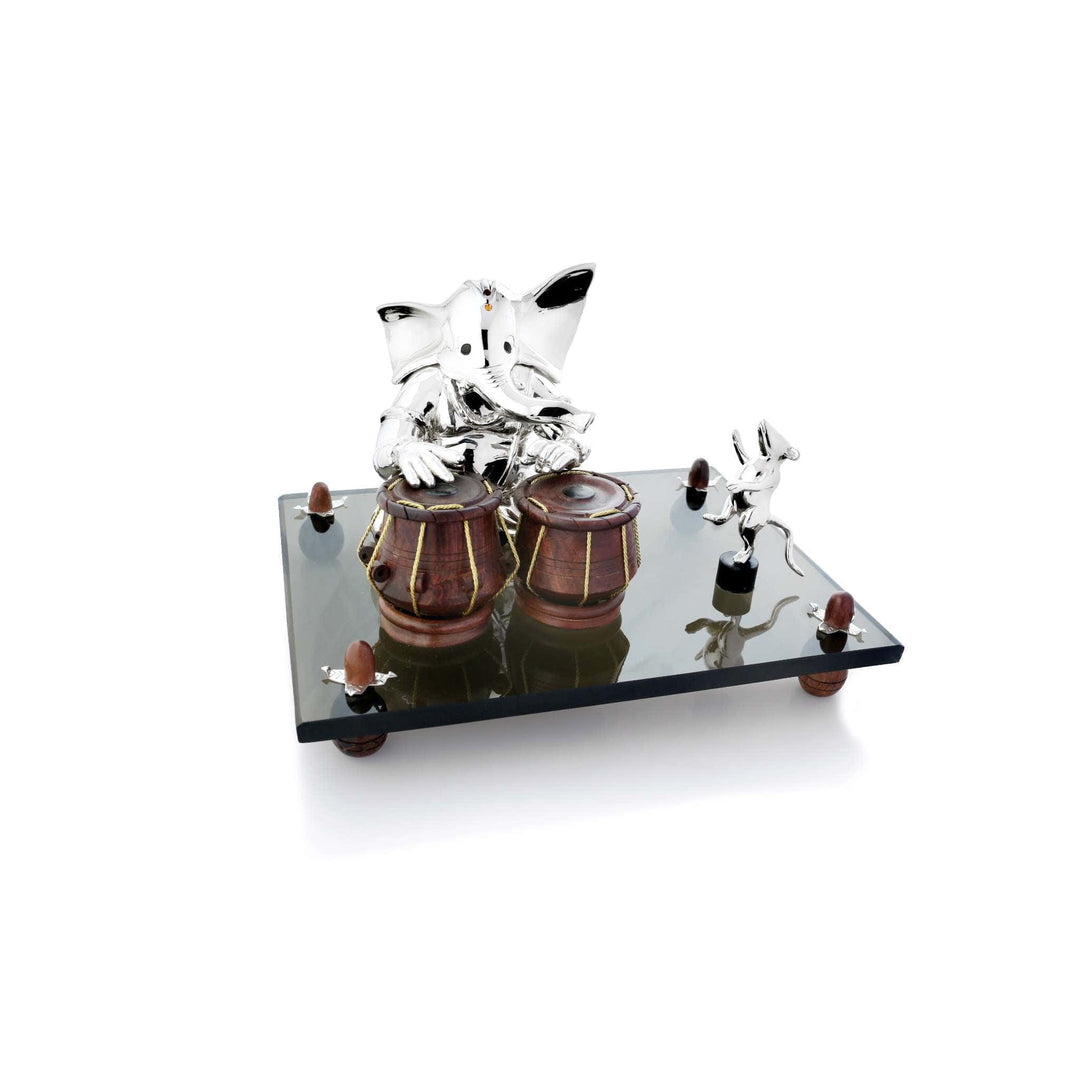 Ganesh Tabla With Wooden Instrument sits a sterling silver Ganesha idol with hands poised mid rhythm over a pair of tabla drums finished in natural wood bound with cord - white background