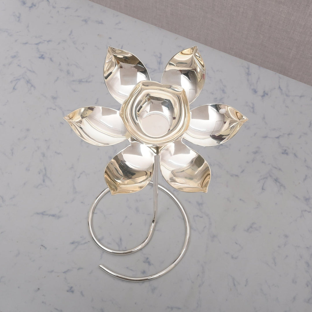 Lotus on Stand is a silver candle stand shaped as a lotus flower opening atop a slim rod - white background