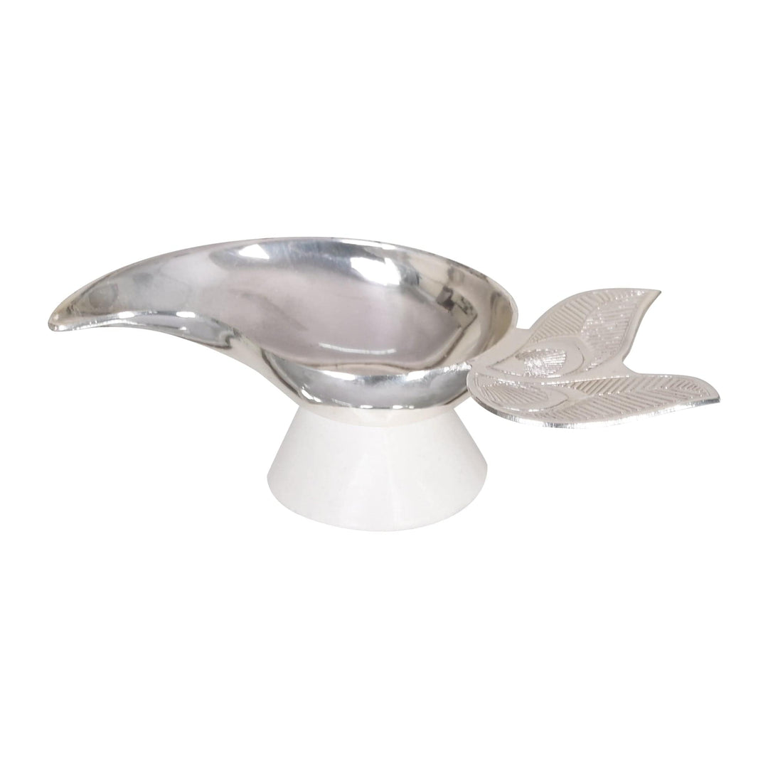 Diya Pihu shapes a silver diya as a single curved leaf, its pointed spout resting on a smooth white pedestal base for a clean - white background