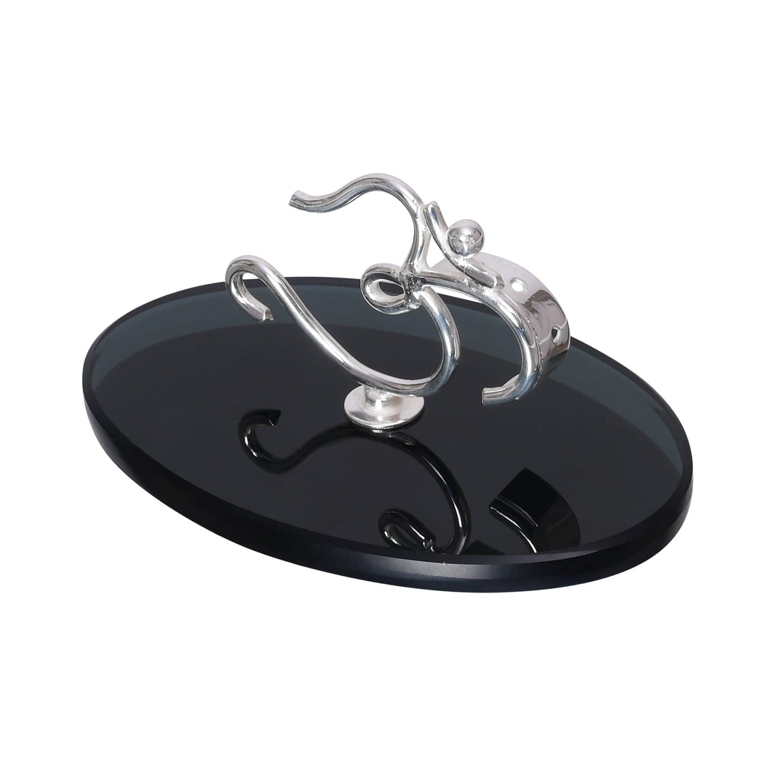 Om Incense Holder is a silver incense holder in which the Om symbol curls upward from a flat black oval base - white background