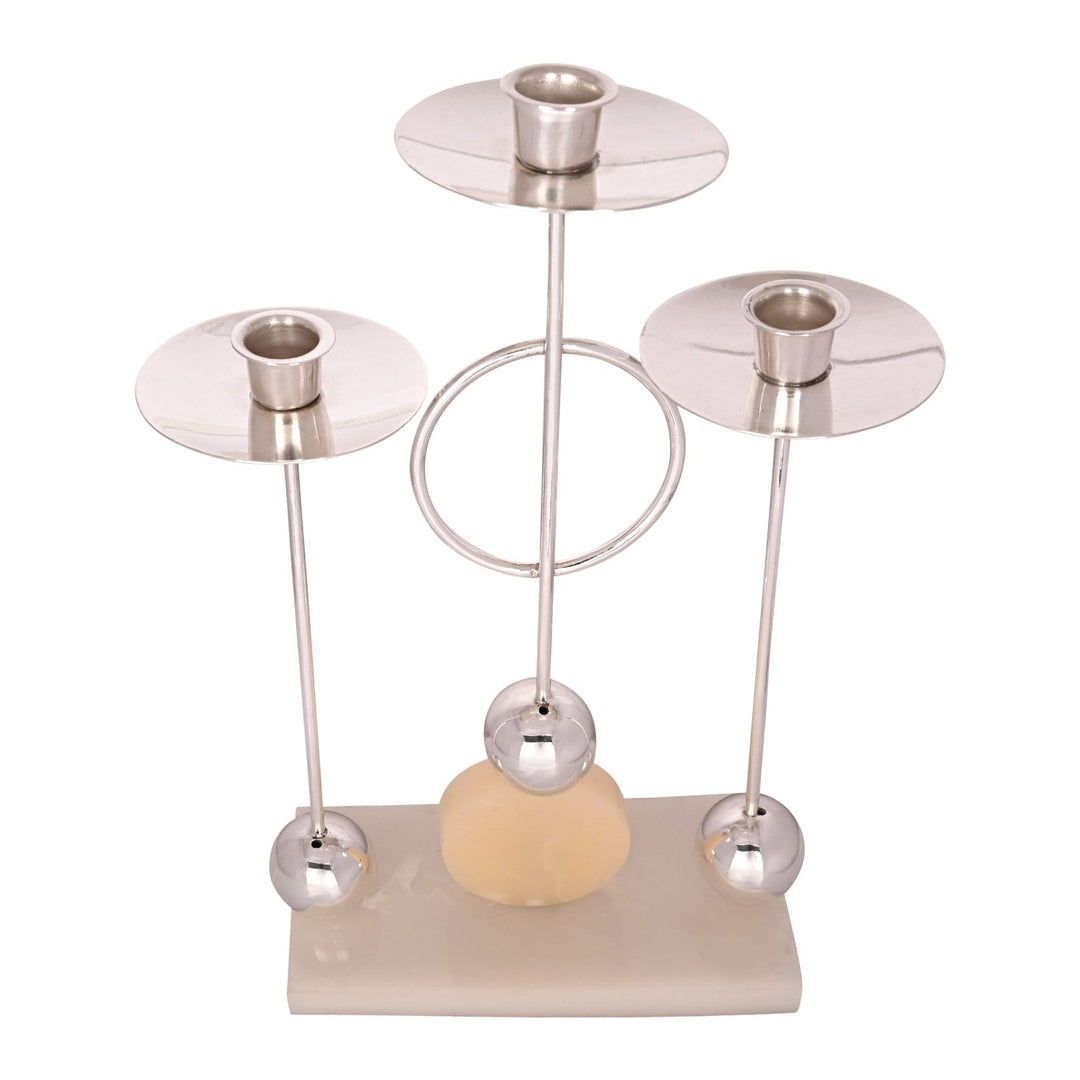 Candlestand 3 Lite Beacon is a silver candlestand that rises on slender stems from a pale stone base, each stem topped with a wide - white background