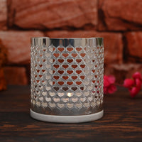 Heart Votive is a cylindrical silver candle stand pierced all over with a dense heart lattice, so a lit tealight throws a soft – Large