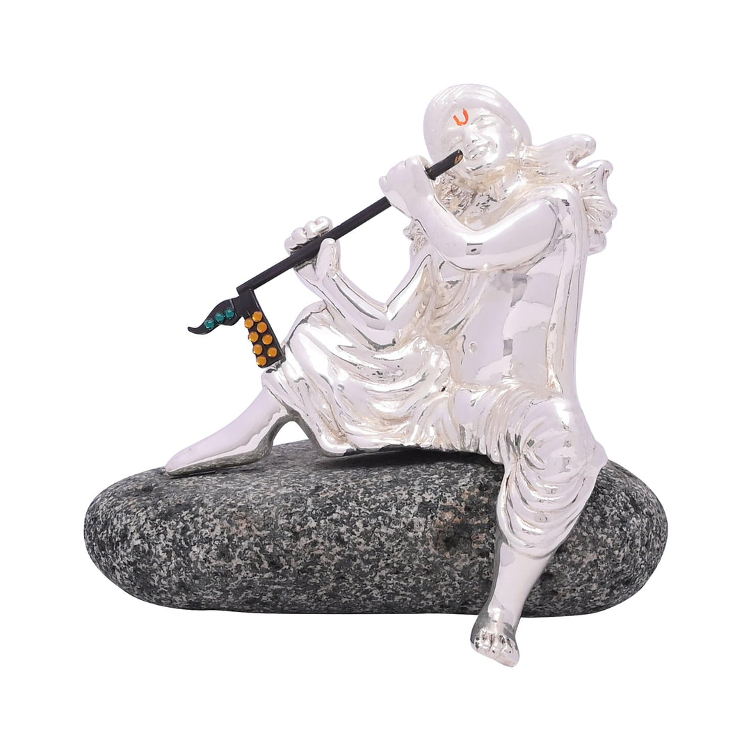 Murli Krishna captures a sterling silver idol of Krishna leaning back on a rock, flute raised to his lips mid-song - white background