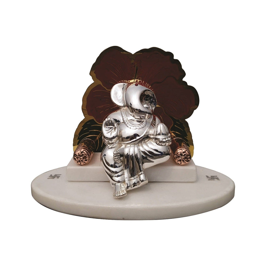 Sinhasan Ganesha is a sterling silver Ganesha idol seated on a throne, one hand raised in blessing and the other cradling a modak - white background