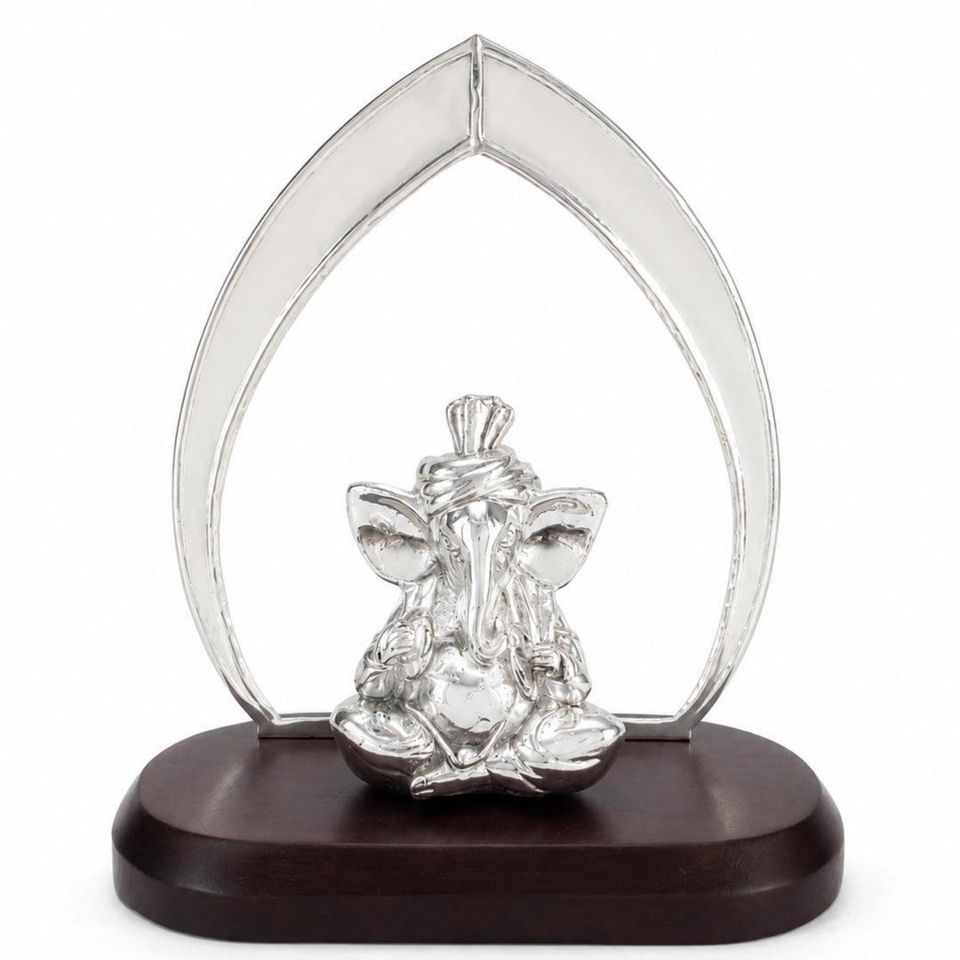 Arch Ganesha is a silver ganesh idol seated in front of a tall pointed arch on an oval dark wood plinth - white background