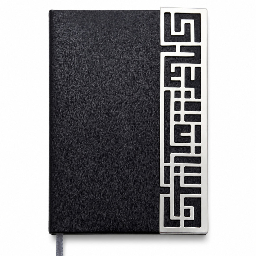 Enigma Diary is a silver diary carrying a geometric maze fretwork strip along one edge of a black leatherette cover. - white background