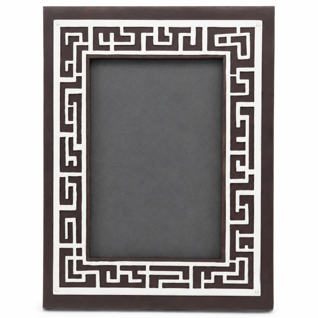 The Enigma Photoframe is a silver photo frame whose dark brown wood face carries a dense geometric fretwork maze border - white background