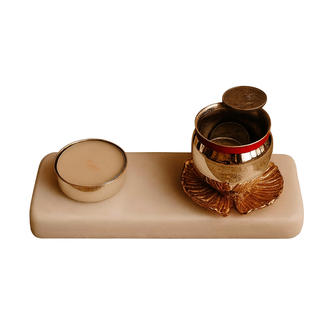 Prarthna Jal Votive is a silver votive pairing a small candle holder with a lotus-footed vessel, both set on a rectangular stone base - white background