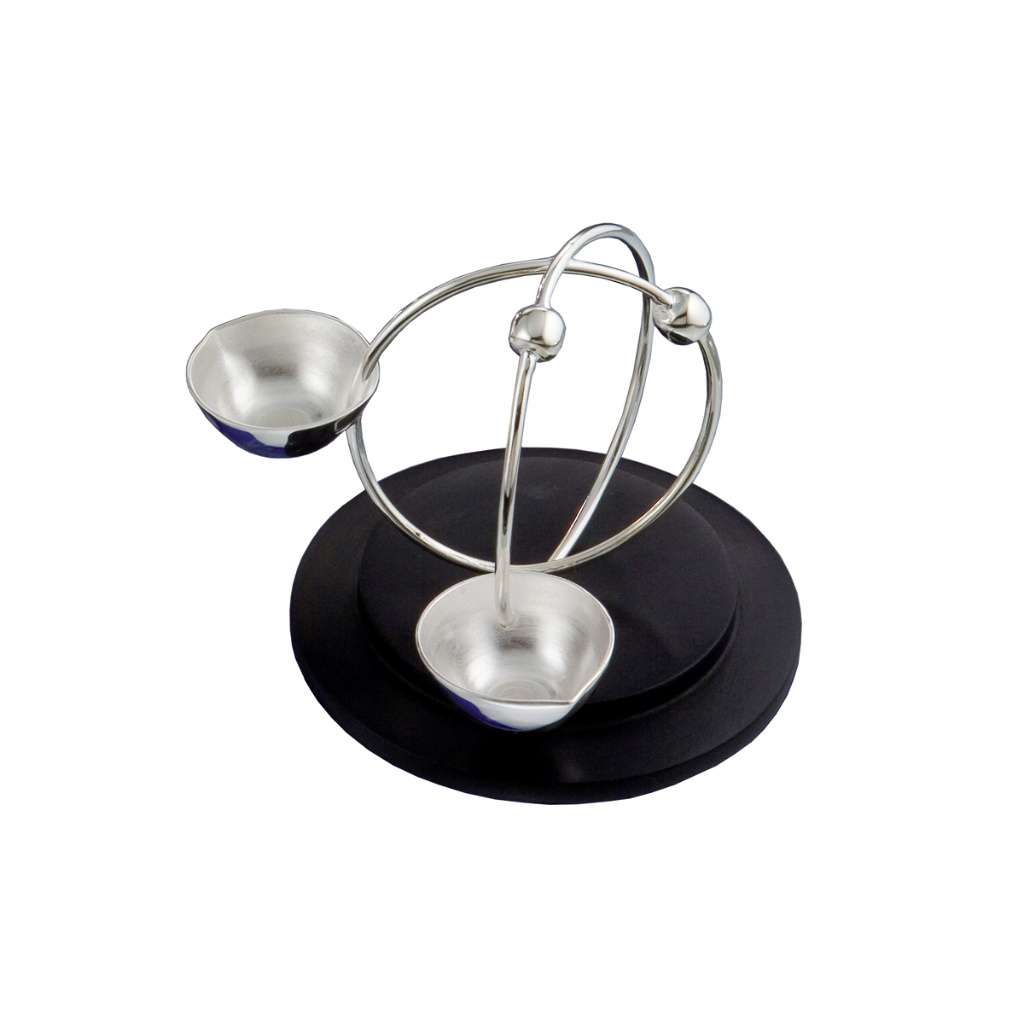 Diya Cosmic is a silver diya that trades the usual flower form for two bowls balanced on intersecting rings - white background