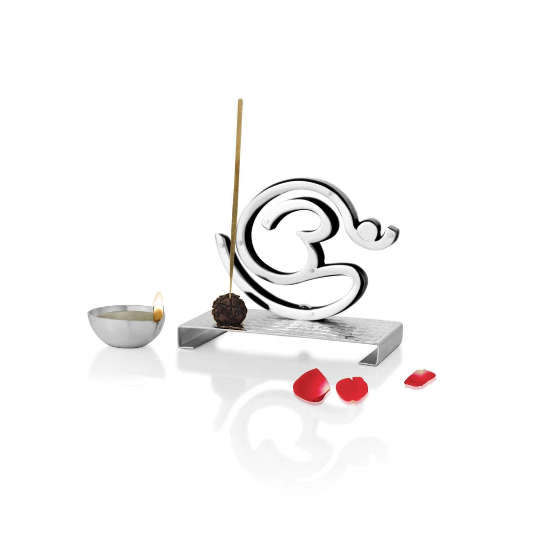 Diya Shlok is a silver diya pairing a raised Om symbol with a small handheld oil cup and a rudraksh bead that doubles as an incense holder - white background
