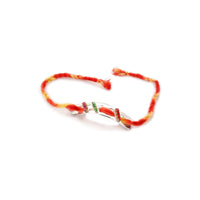 Rakhi Mauli is a silver rakhi with a curved bar set with rows of pink, green and red stones on a red and yellow braided thread. - white background