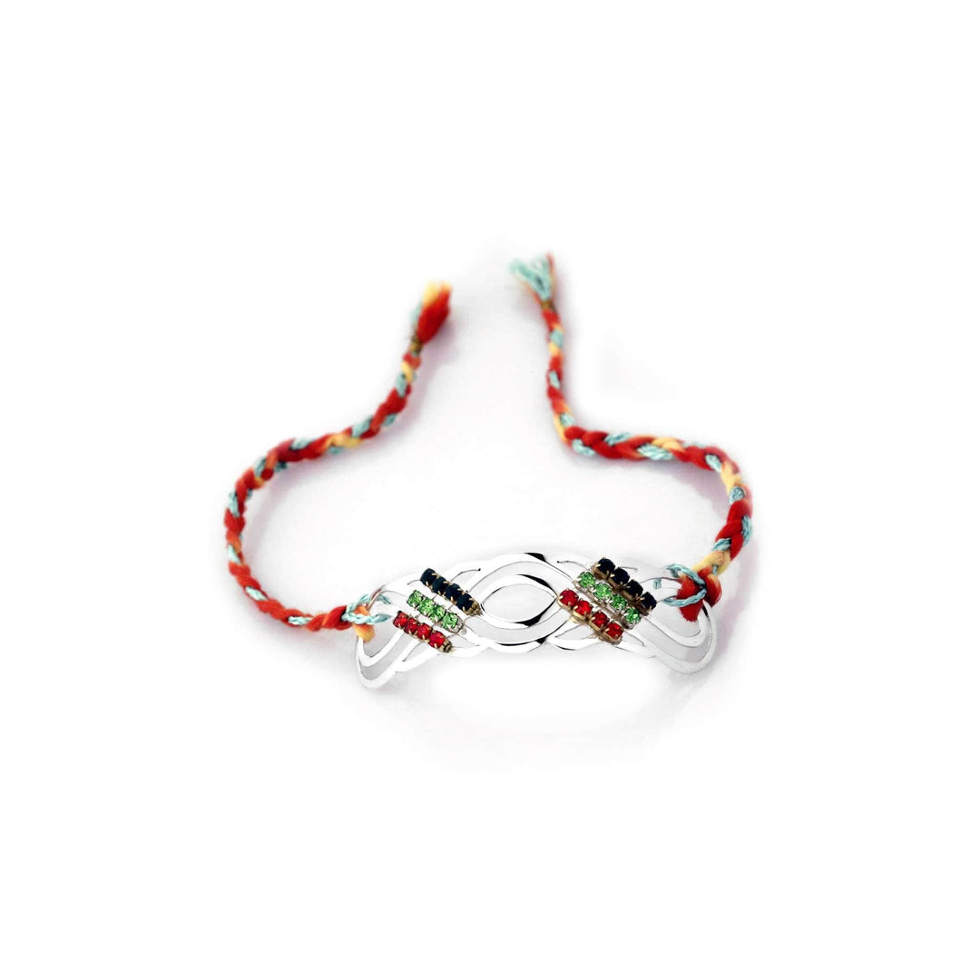 Rakhi Kalava is a silver rakhi with an openwork wave-shaped medallion set with rows of black, green and red stones on a multicolour braided thread. - white background