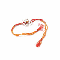 Rakhi Divine is a silver rakhi with a floral-shaped medallion set with a single amber stone on a red, orange and gold braided thread. - white background