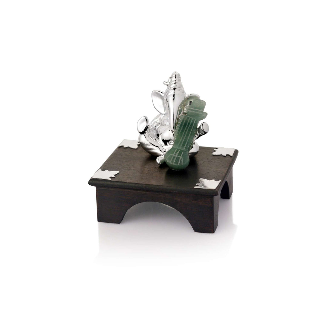 Ganesh Veena rests a veena carved in soft green stone across one arm of a sterling silver Ganesha idol - white background