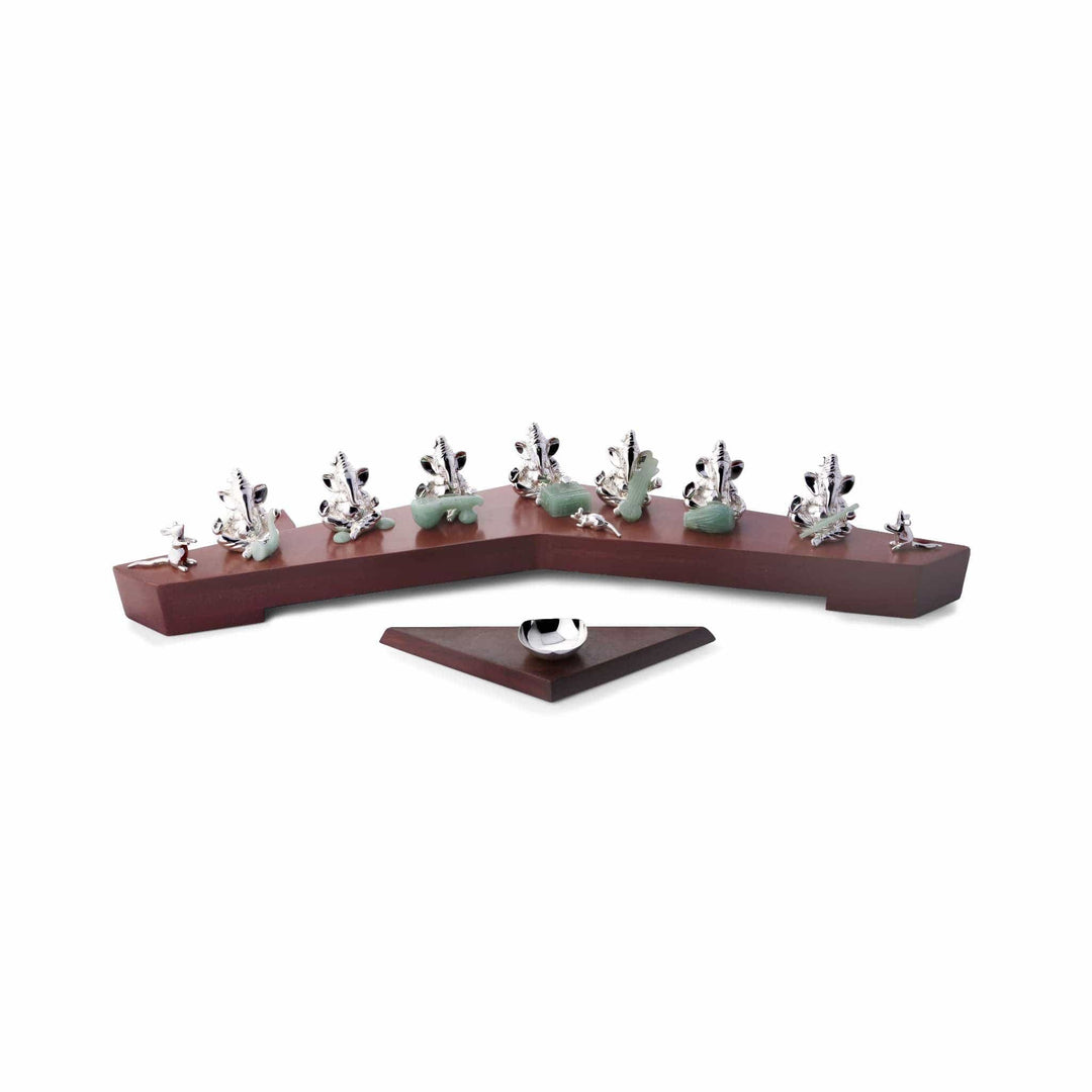 Ganesh Saptarishi lines up seven individually cast sterling silver Ganesha idols along a boomerang-shaped rosewood tray - white background