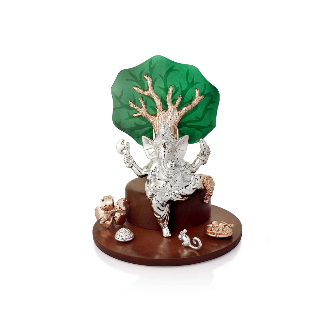 Ganesh Kshipra is a four-armed sterling silver Ganesha idol that dances beneath a rose gold kalpavriksha tree - white background
