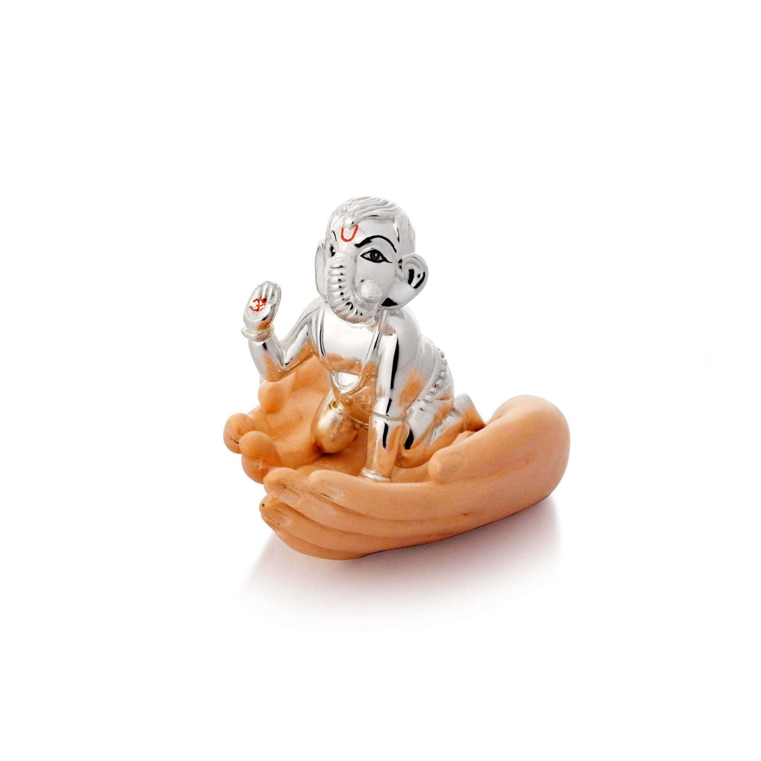 Ganesh Vardaan shows Ganesha as a child figure, a sterling silver idol seated in a pair of open, cupped hands finished in a warm skin tone - white background