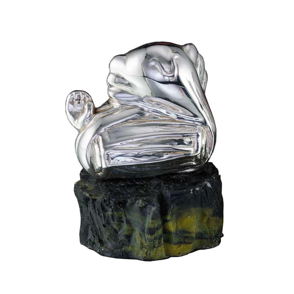 Ganesh Dholaki shows a sterling silver Ganesha idol reclining at ease, one arm curled near his head, resting on a rugged - white background