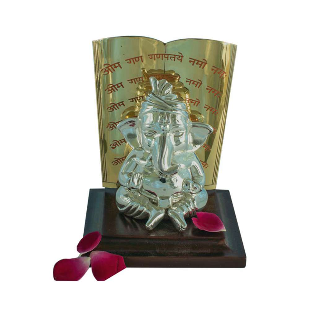 Ganesh Pustak sets a crowned, seated sterling silver Ganesha idol linked to knowledge and learning against an open book cast in gold tone - white background